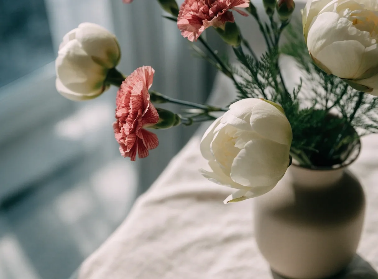 Small white blooms in a vase beside kraft paper on a bench